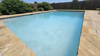 Swimming pool filled with cloudy, milky pale-blue water
