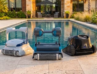 Dolphin Sigma, Premier and Quantum robotic pool cleaners beside an inground pool